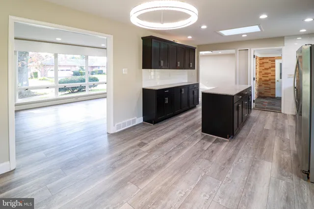 a living room with stainless steel appliances kitchen island granite countertop a large window and a flat screen tv