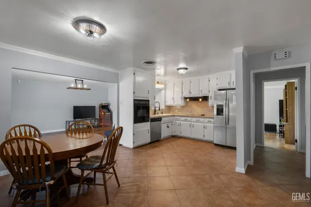 a kitchen with a dining table chairs and refrigerator