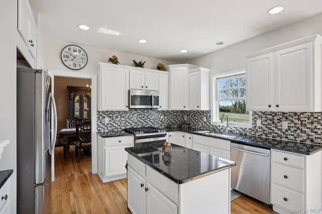 a kitchen with granite countertop a sink a stove top oven and cabinets