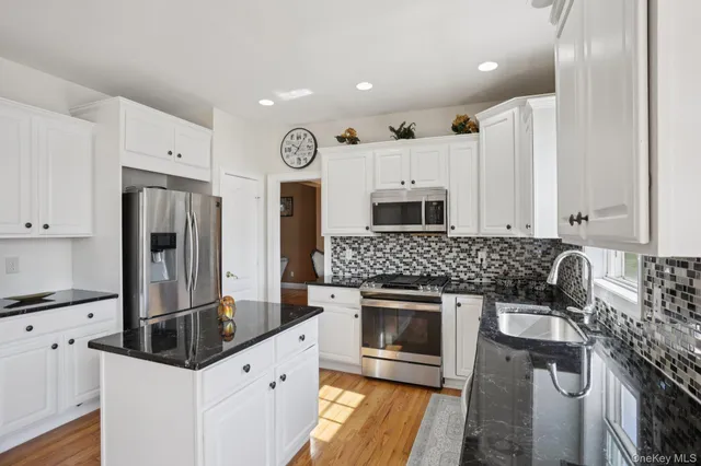 a kitchen with stainless steel appliances granite countertop a stove a sink and a refrigerator