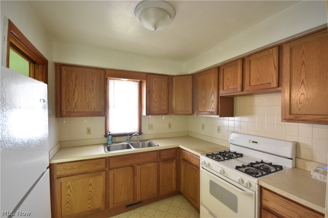 31921 Pendley Road Willowick, OH 44095 - Photo 7 of 22 Kitchen with white appliances, sink, tasteful backsplash, and light tile flooring