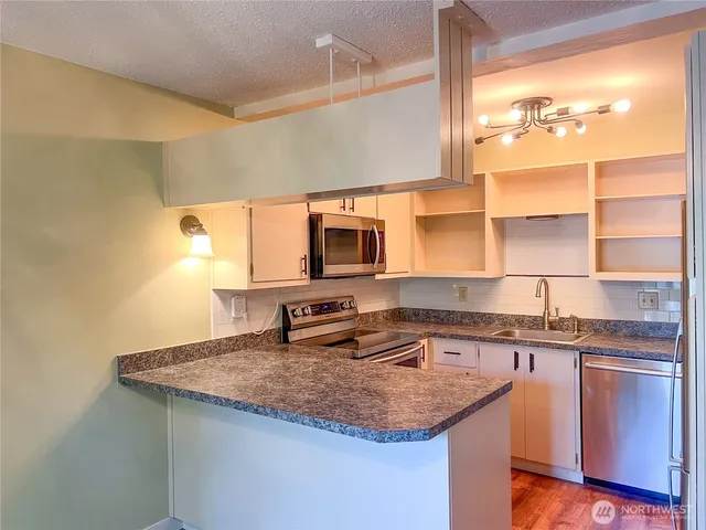 a kitchen with stainless steel appliances granite countertop a sink stove and cabinets