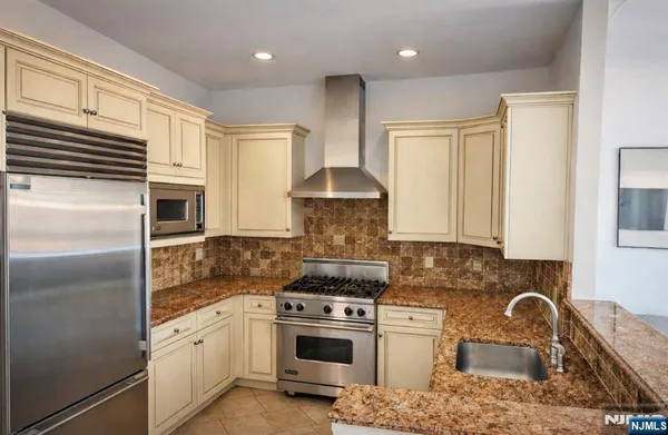 a kitchen with stainless steel appliances granite countertop a stove a sink and a refrigerator