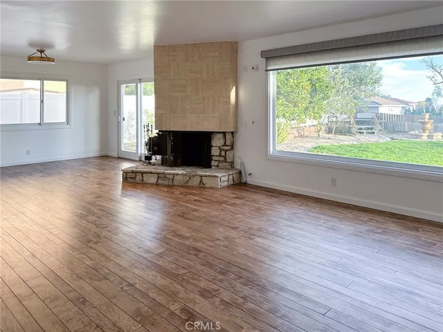 a view of empty room with wooden floor and fireplace