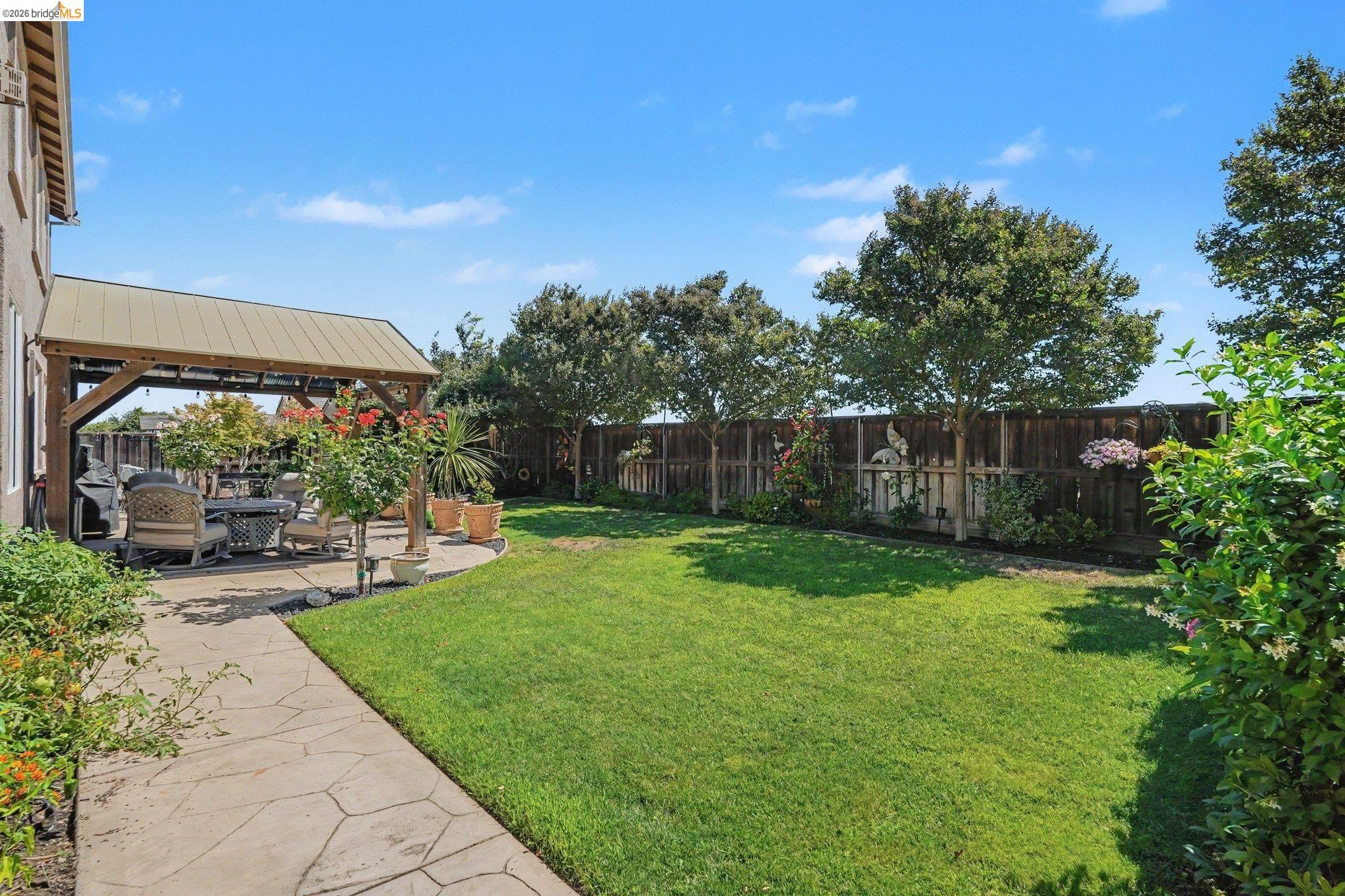 106 Little Ranch Circle Oakley, CA 94561 - Photo 27 of 34 Expansive backyard featuring a stamped concrete patio with a covered pergola, a lush lawn, mature trees, and a wooden privacy fence