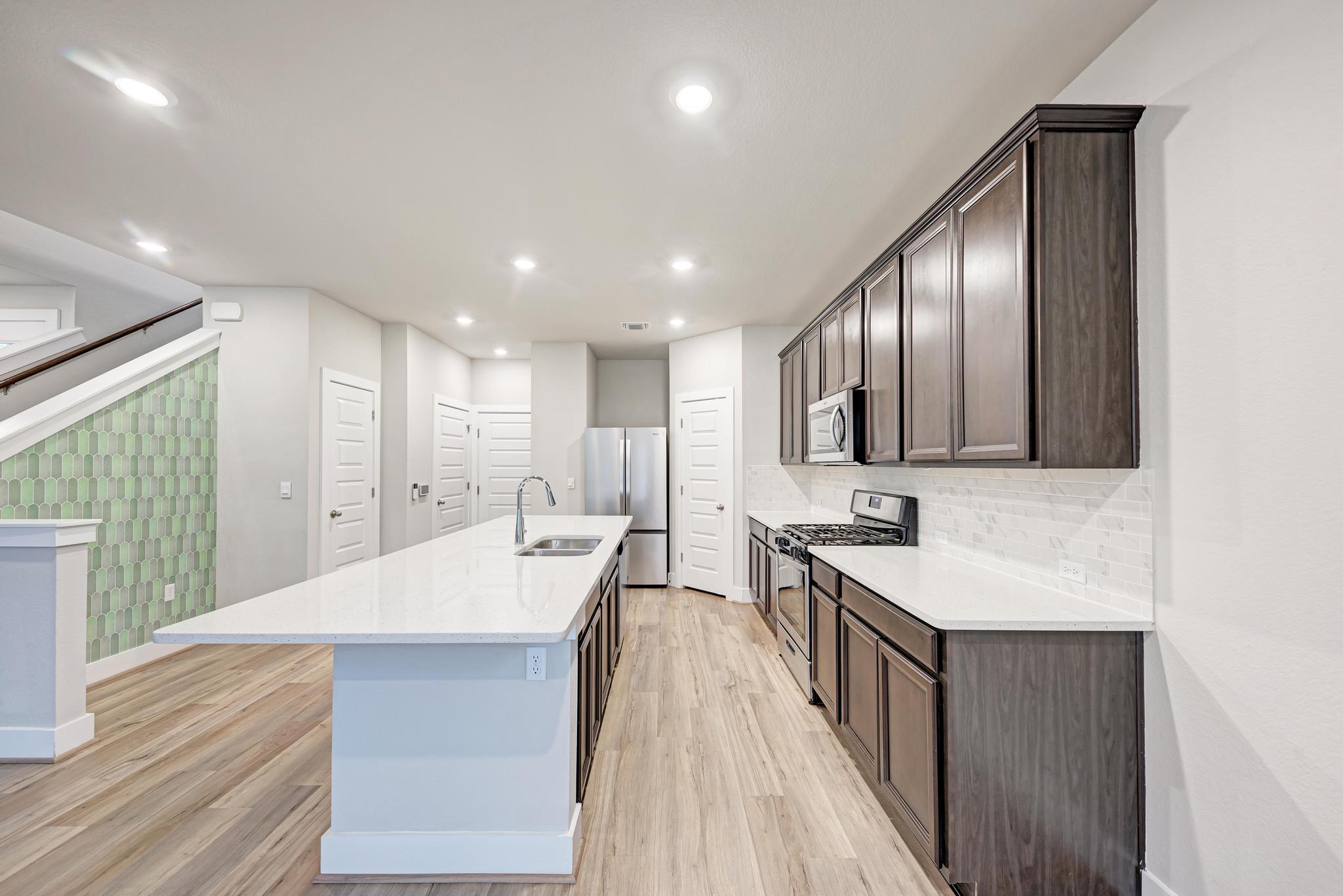 7319 Travertine Spring Drive, Unit 115 Austin, TX 78744 - Photo 18 of 37 a hall with stainless steel appliances granite countertop a sink dishwasher a stove and a oven with wooden floor