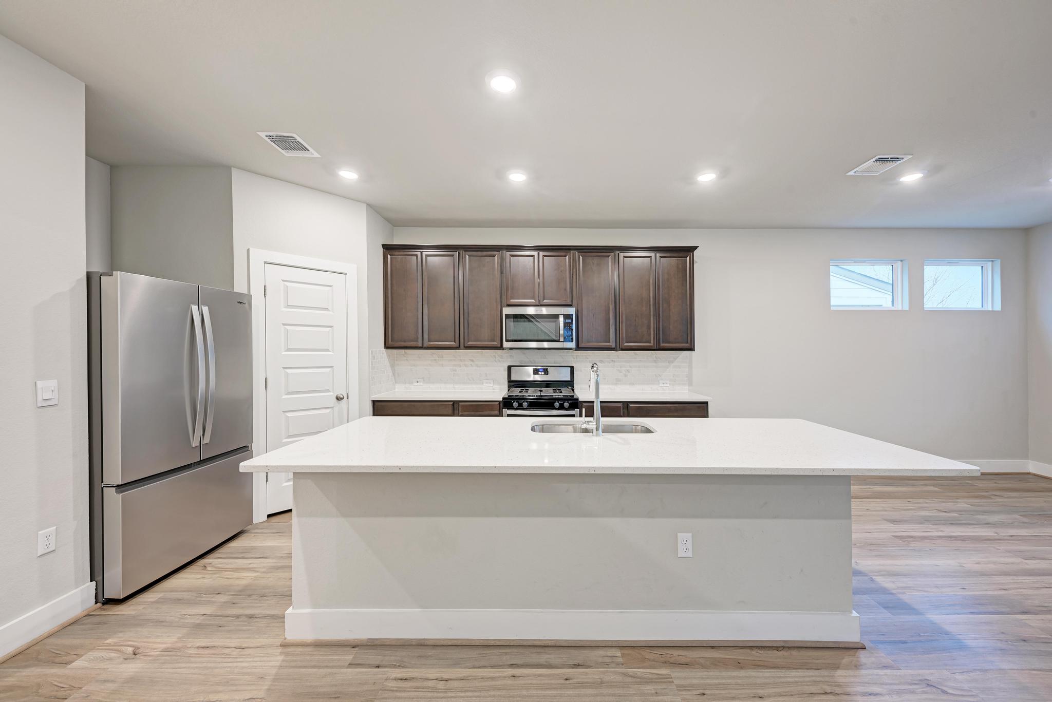 7319 Travertine Spring Drive, Unit 115 Austin, TX 78744 - Photo 19 of 37 a large kitchen with kitchen island a large counter top stainless steel appliances and cabinets