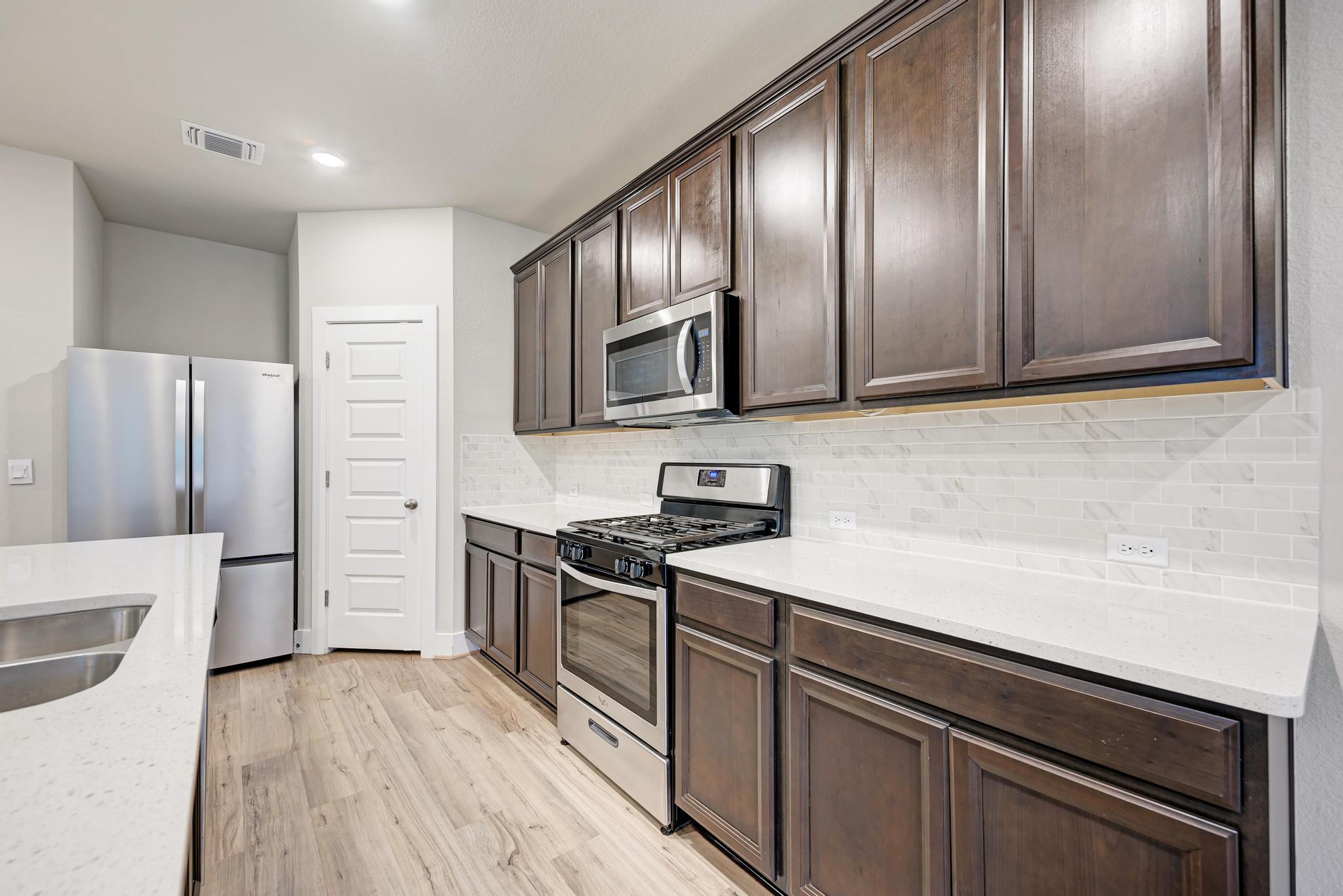 7319 Travertine Spring Drive, Unit 115 Austin, TX 78744 - Photo 21 of 37 a kitchen with stainless steel appliances granite countertop a refrigerator stove and sink