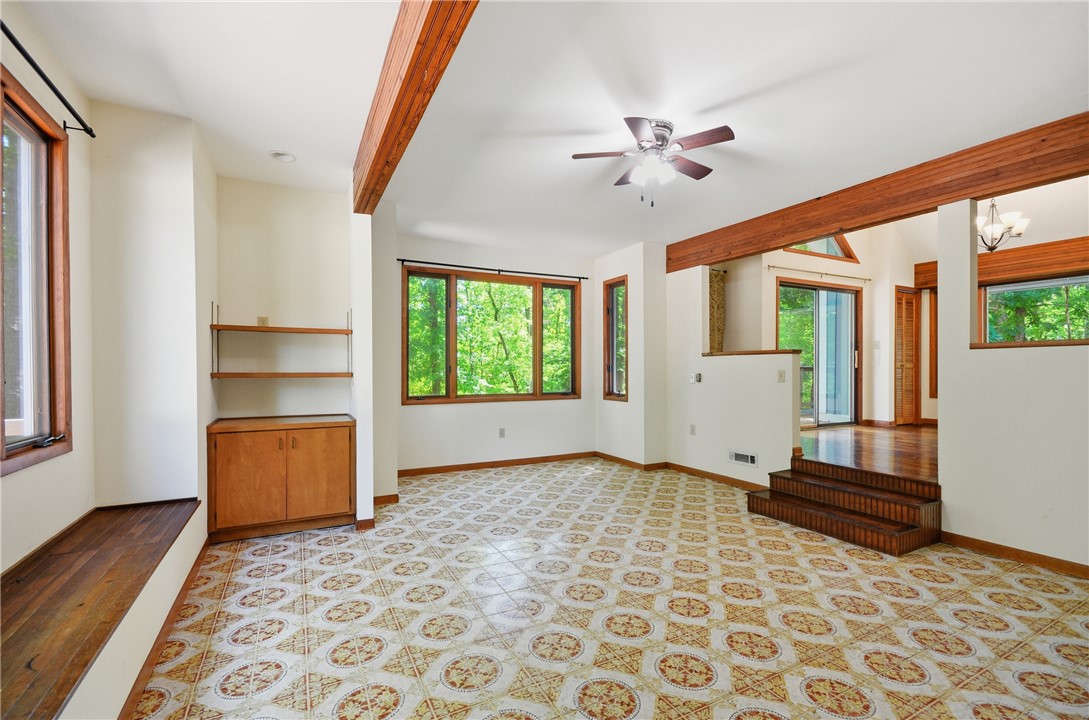 1298 Carradine Road Seneca, SC 29678 - Photo 23 of 43 Bright interior living area with exposed wooden beams and large windows offering verdant outdoor views.