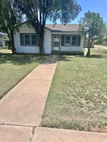 a view of a yard in front of a house with a large tree