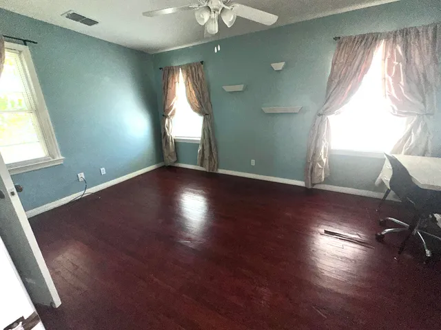 an empty room with wooden floor and windows