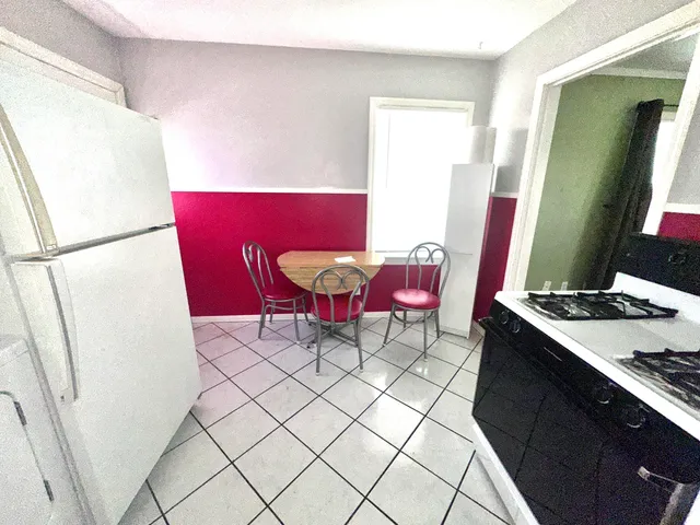 a living room with furniture and a refrigerator