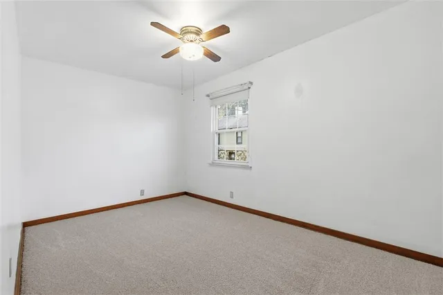 an empty room with a ceiling fan and a window