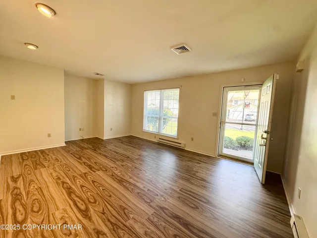 a view of empty room with wooden floor and fan