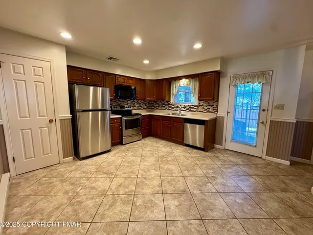 a kitchen with stainless steel appliances granite countertop a refrigerator and a stove top oven