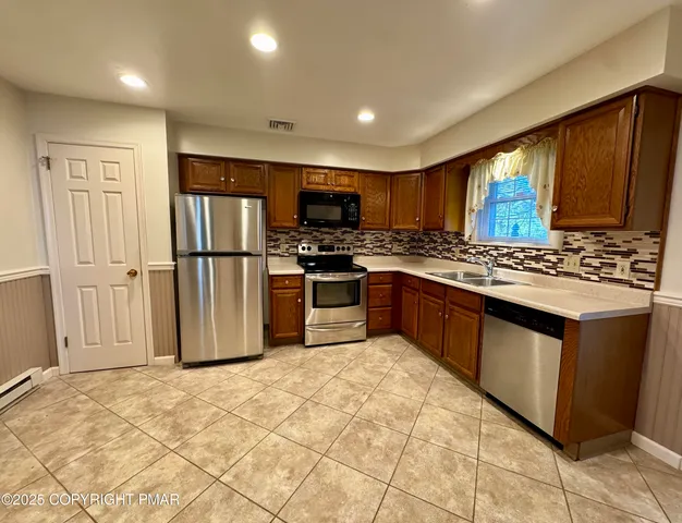 a kitchen with stainless steel appliances granite countertop a stove top oven a refrigerator and a sink with granite countertops