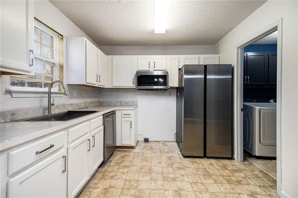 a kitchen with stainless steel appliances granite countertop a refrigerator a stove and a sink