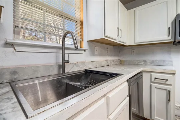 a kitchen with granite countertop white cabinets and a sink