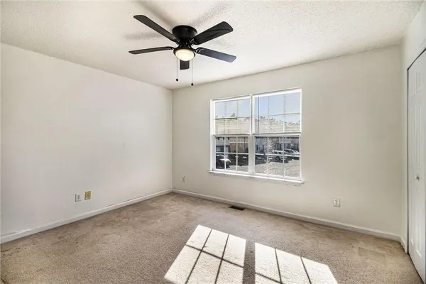 an empty room with a window and a fan