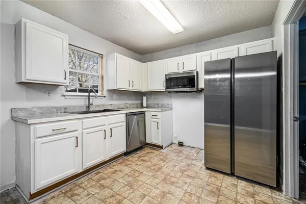 a kitchen with a refrigerator sink and cabinets