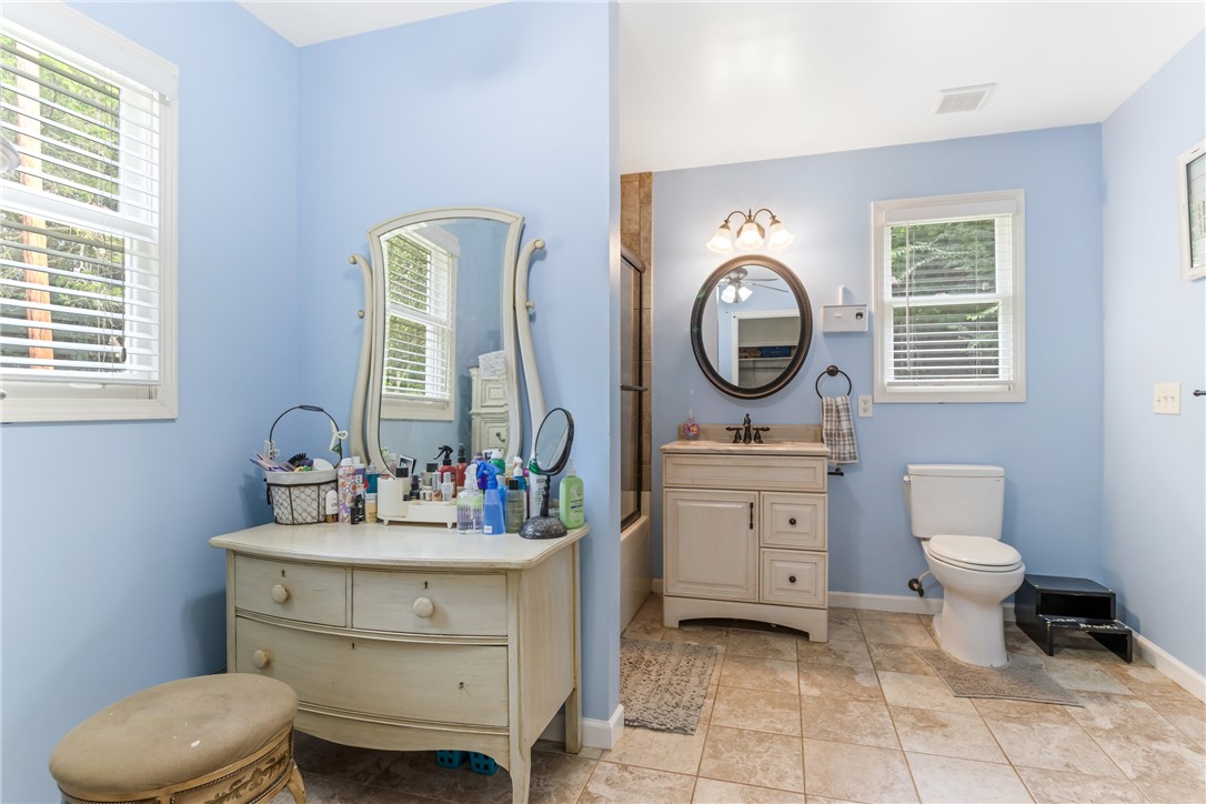 404 Davis Road Liberty, SC 29657 - Photo 26 of 39 Functional bathroom features a practical vanity with a circular mirror and a separate dressing area with a large mirrored dresser.