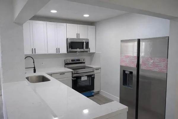 a kitchen with stainless steel appliances a stove a sink a refrigerator and cabinets