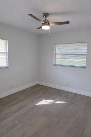 en empty room with wooden floor fan and window