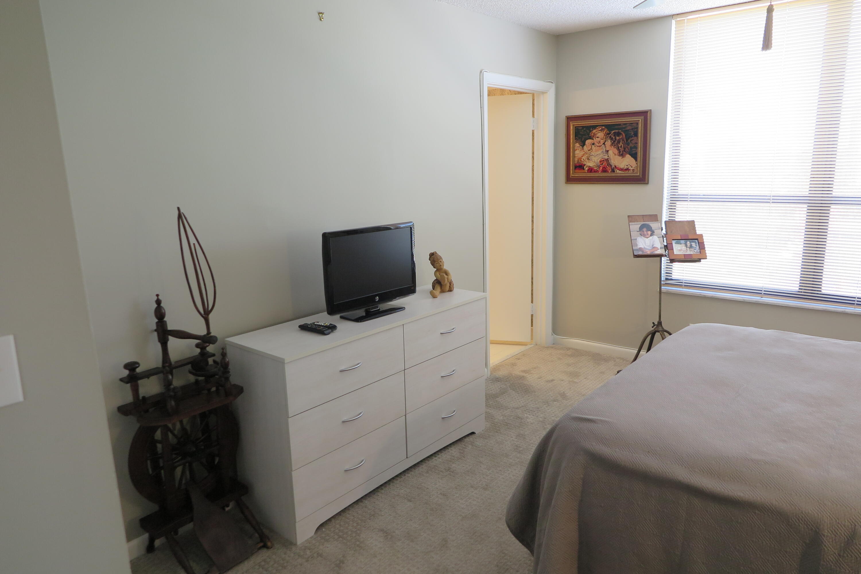 7578 Regency Lake Drive, Unit 501 Boca Raton, FL 33433 - Photo 20 of 32 a bedroom with a bed and a flat screen tv
