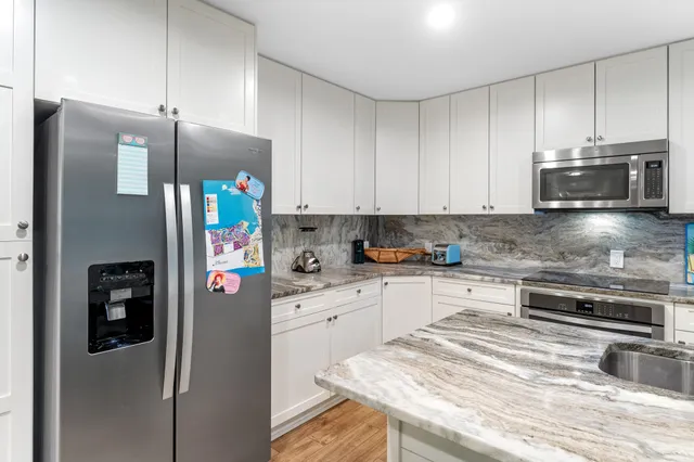 a kitchen with stainless steel appliances granite countertop a refrigerator a stove and a sink with granite countertops