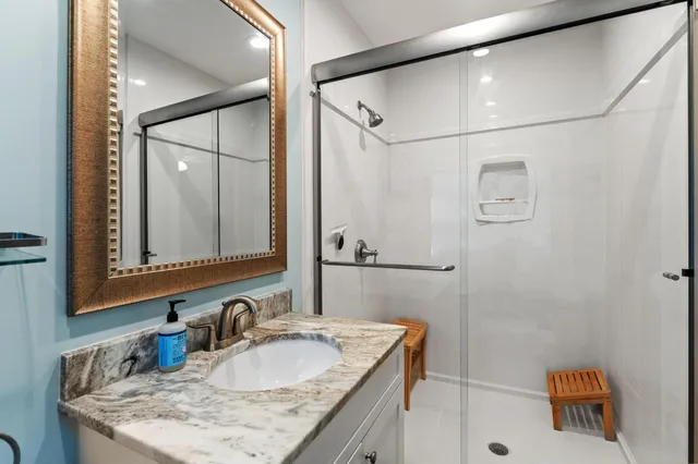 a bathroom with a granite countertop sink mirror vanity and shower