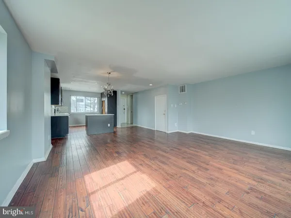 a view of a living hall with wooden floor and a kitchen