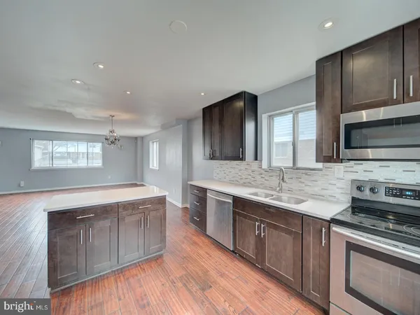 a large kitchen with stainless steel appliances wooden cabinets and a stove top oven
