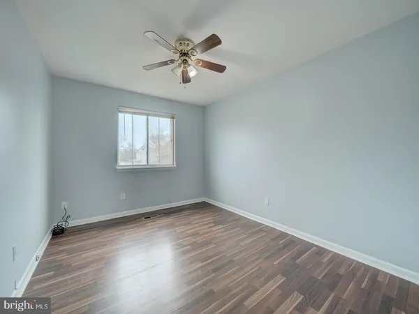 an empty room with wooden floor chandelier fan and windows