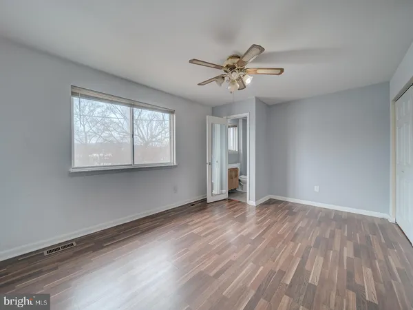 a view of empty room with wooden floor and fan