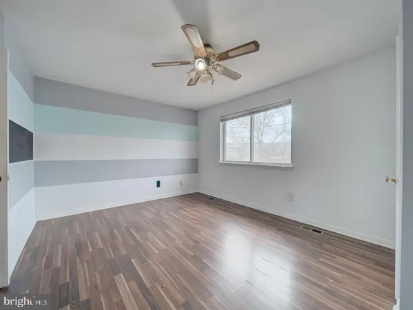 an empty room with wooden floor fan and windows