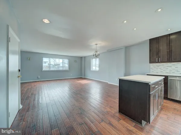 a view of a kitchen and an empty room with wooden floor and a window
