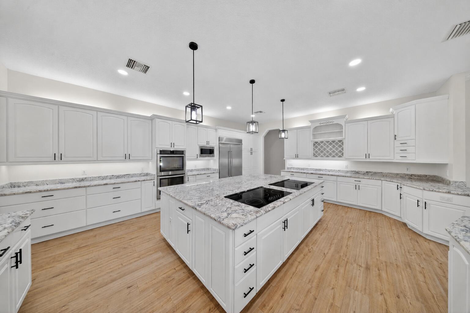 8686 Andrews Avenue Fort Pierce, FL 34945 - Photo 17 of 76 a large white kitchen with a stove a sink a center island and wooden floor