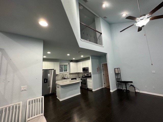a kitchen with stainless steel appliances kitchen island granite countertop a refrigerator a stove a microwave oven a sink with island and chairs with wooden floor
