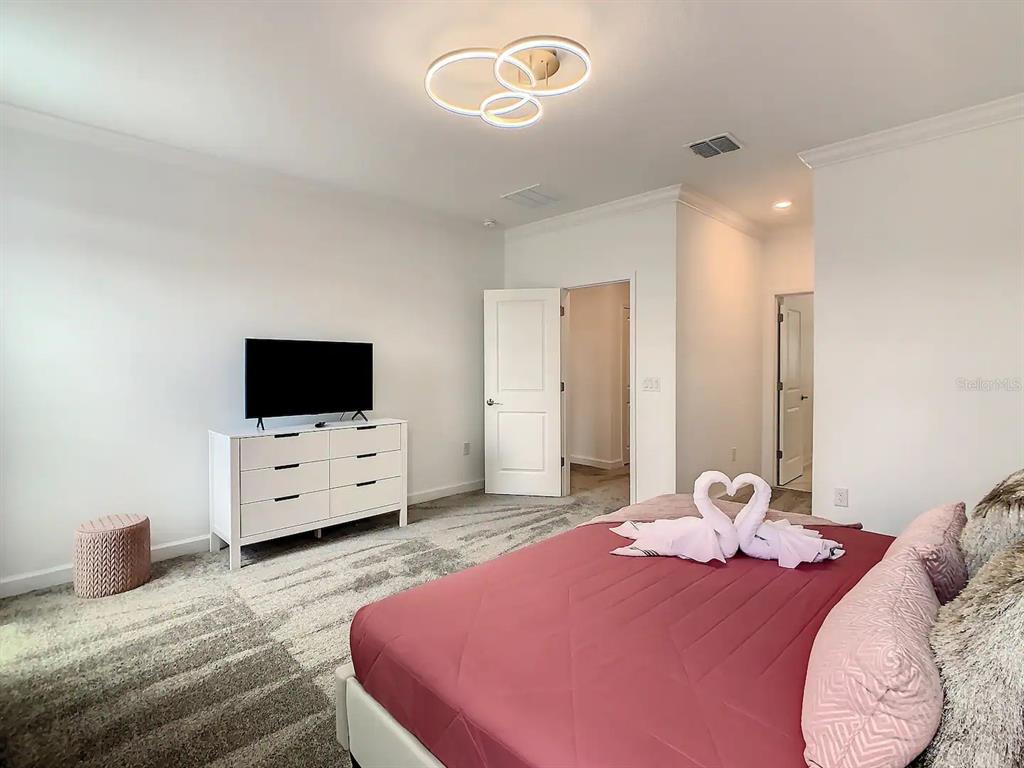 2908 Protagonist Street Kissimmee, FL 34746 - Photo 14 of 32 a bedroom with a bed and flat screen tv