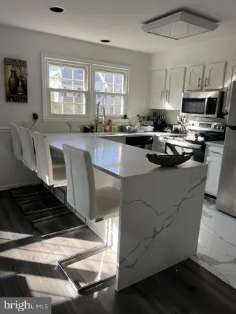 a kitchen with stainless steel appliances granite countertop a stove a sink dishwasher a microwave oven and a dining table with wooden floor