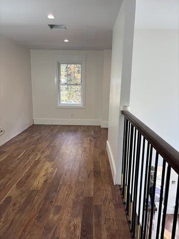 a view of a hallway with wooden floor and a window