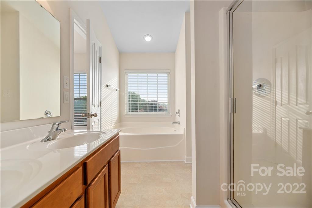 5133 Prosperity Church Road Charlotte, NC 28269 - Photo 21 of 37 a bathroom with a double vanity sink a mirror and a bathtub