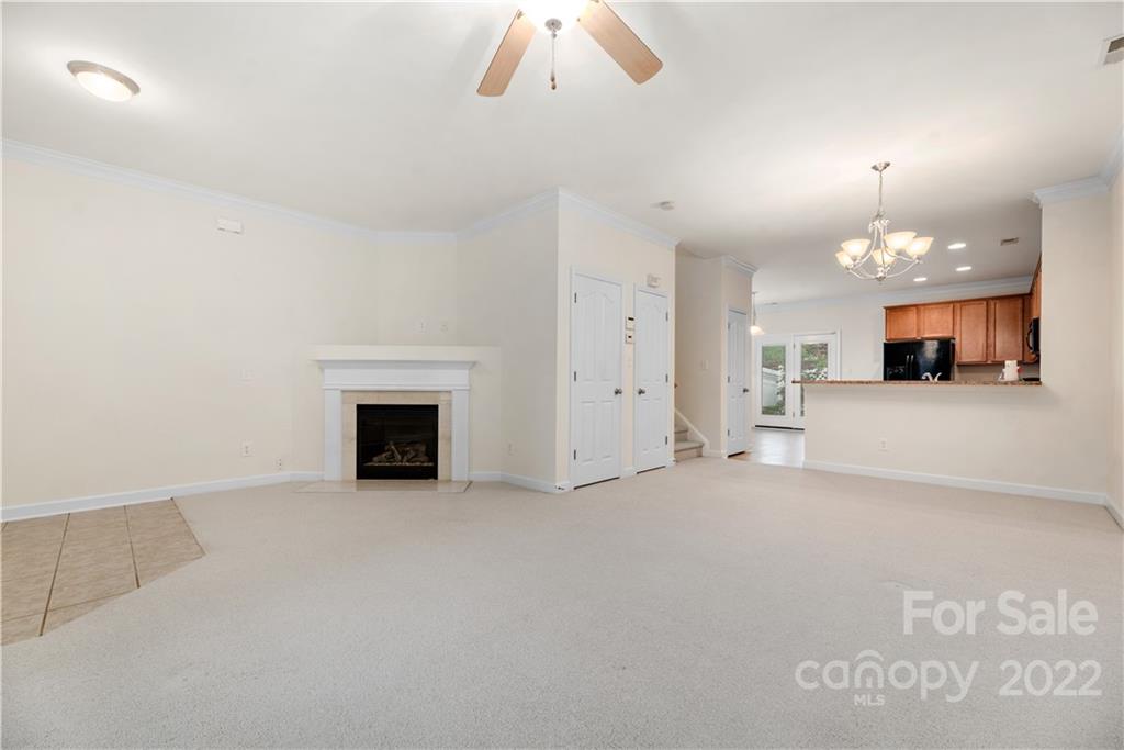 5133 Prosperity Church Road Charlotte, NC 28269 - Photo 5 of 37 an empty room with a fireplace and chandelier fan