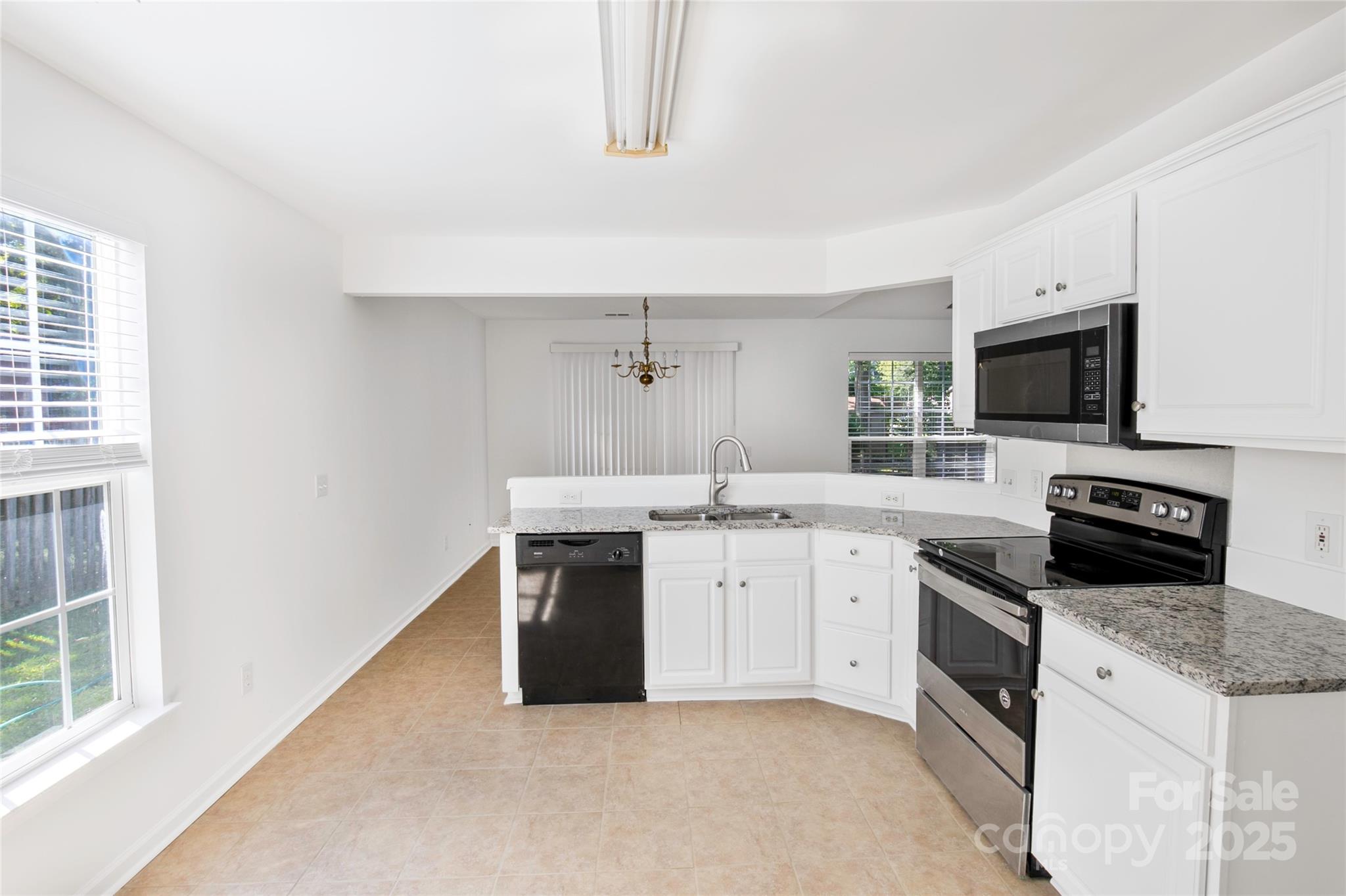 14034 Dingess Road, Unit 101 Charlotte, NC 28273 - Photo 4 of 24 a kitchen with granite countertop a sink a stove top oven and stainless steel appliances