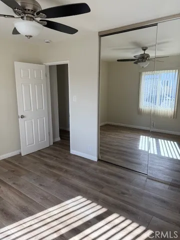 a view of a hallway with wooden floor and a ceiling fan