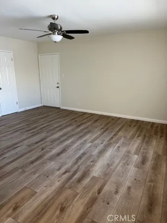 a view of a room with wooden floor and a ceiling fan