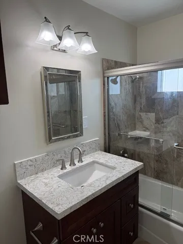 a bathroom with a granite countertop sink a light fixture and a mirror