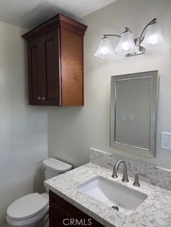 a bathroom with a granite countertop toilet sink and mirror