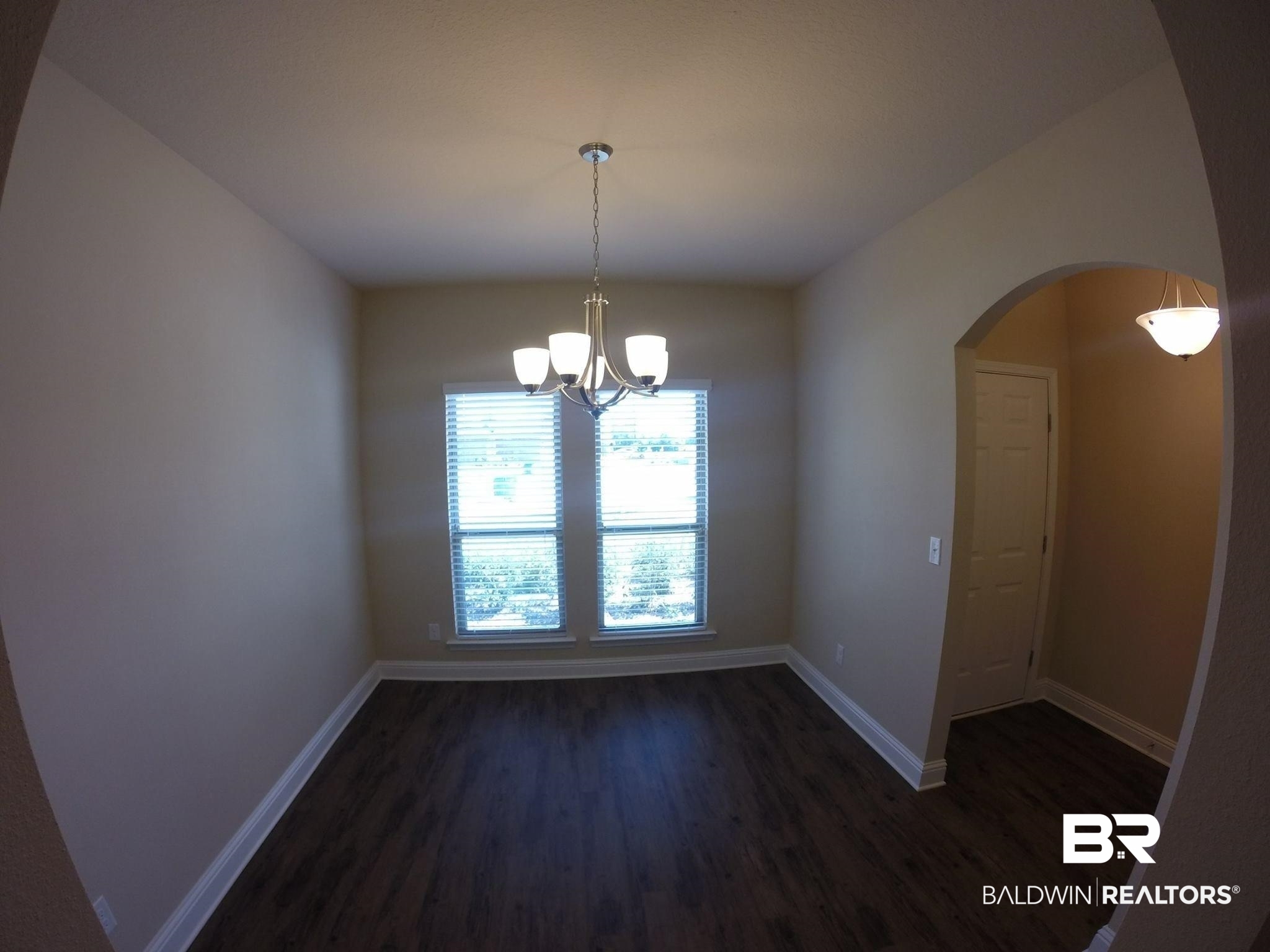2996 Notsram Court Mobile, AL 36695 - Photo 7 of 16 Unfurnished room featuring arched walkways, a notable chandelier, baseboards, and dark wood finished floors