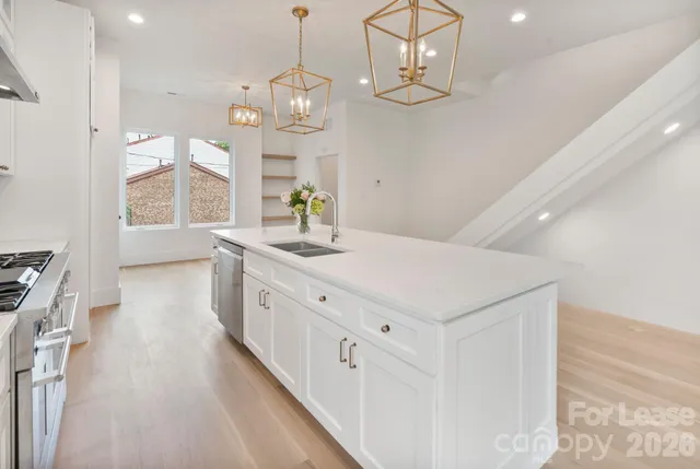 a large white kitchen with a large window a sink a center island and stainless steel appliances